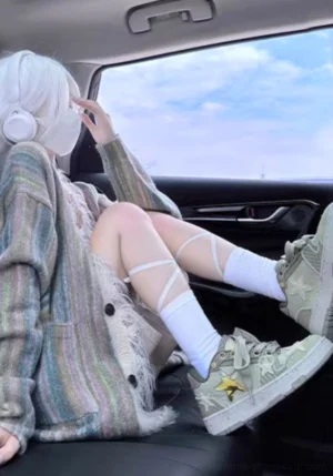 Green Longjing tea star sneakers worn by a woman in a striped cardigan and white socks inside a car for a casual Y2K streetwear outfit