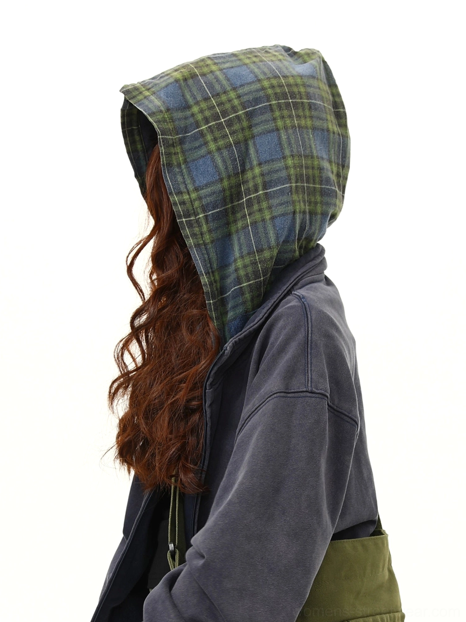 Close-up detail of the green and navy tartan plaid lining inside an oversized hooded streetwear jacket