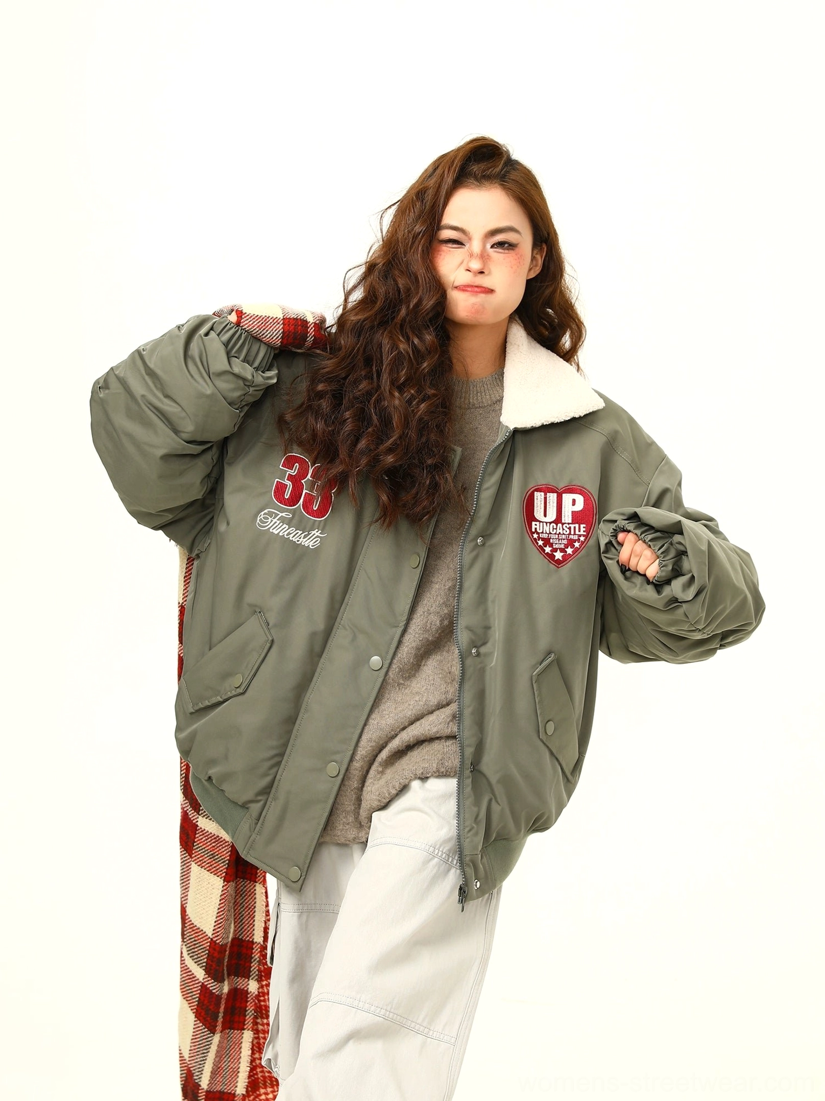 Side view of green oversized varsity bomber jacket with embroidered chest patches and drop shoulders