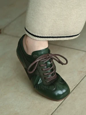 Dark green retro leather sneakers worn with cropped knit pants, featuring brown laces, contrast stitching, and a low-top casual streetwear design