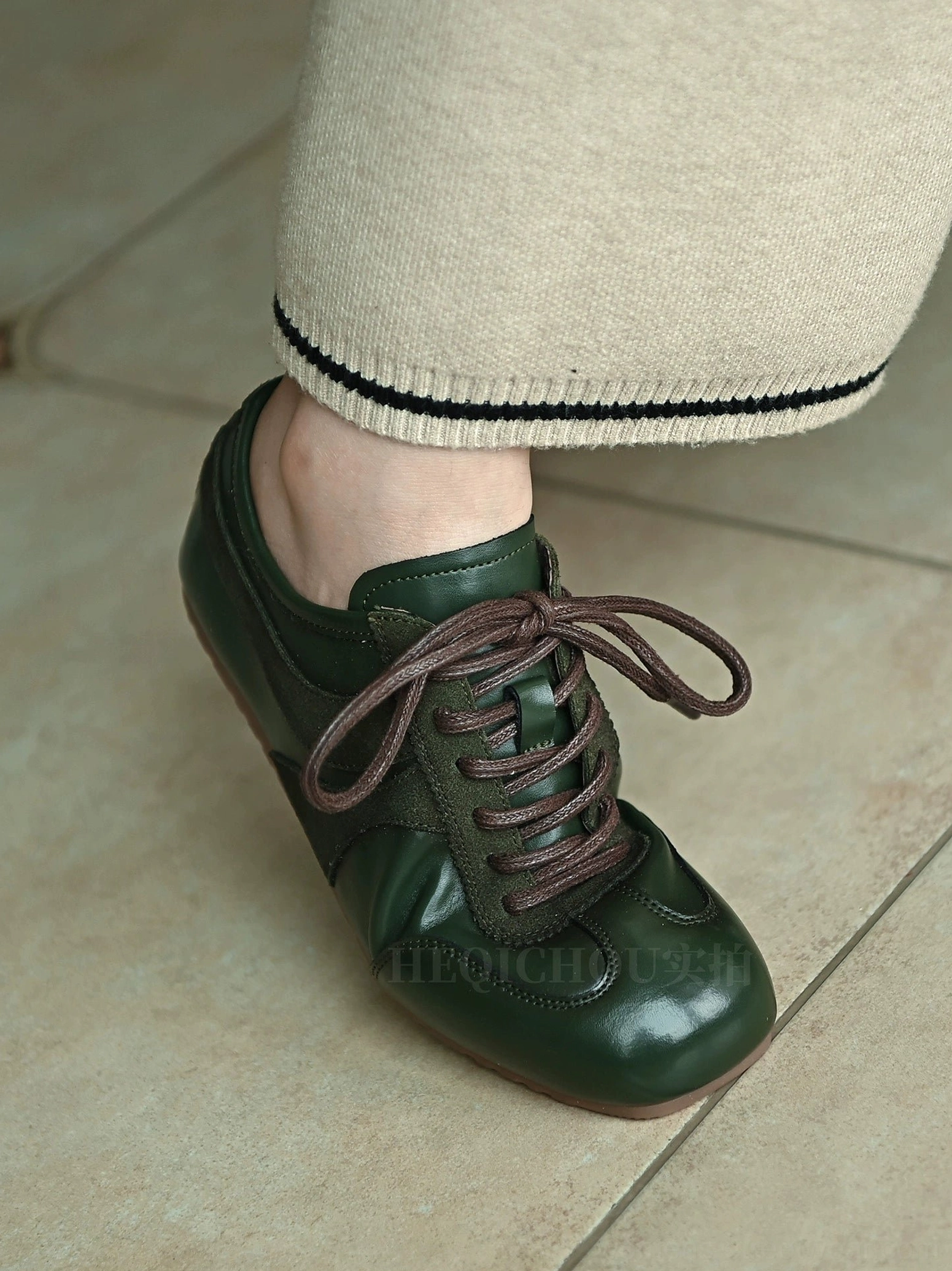 Dark green retro leather sneakers worn with cropped knit pants, featuring brown laces, contrast stitching, and a low-top casual streetwear design