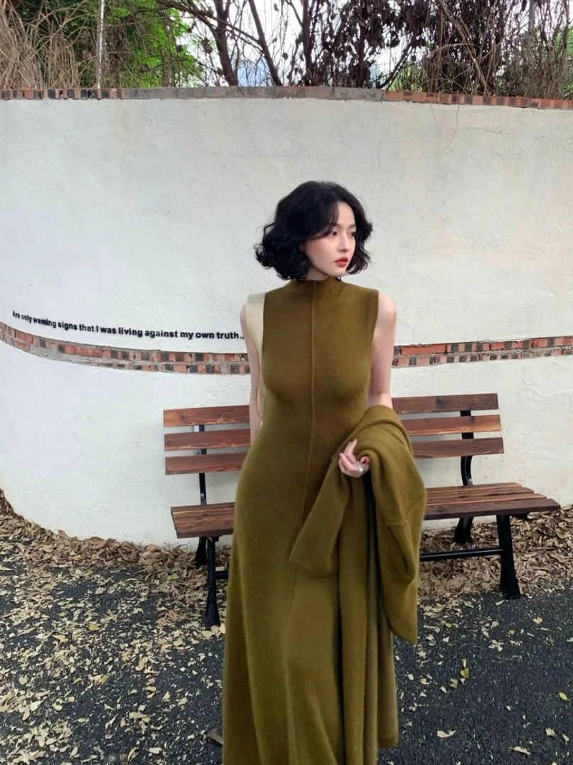 Side view of green fitted sleeveless mock neck maxi knit dress showing the elongated column silhouette and center seam detail