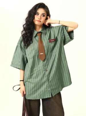Three quarter view of a green striped oversized button down shirt with short sleeves, side slit hem, chest patch, and brown tie