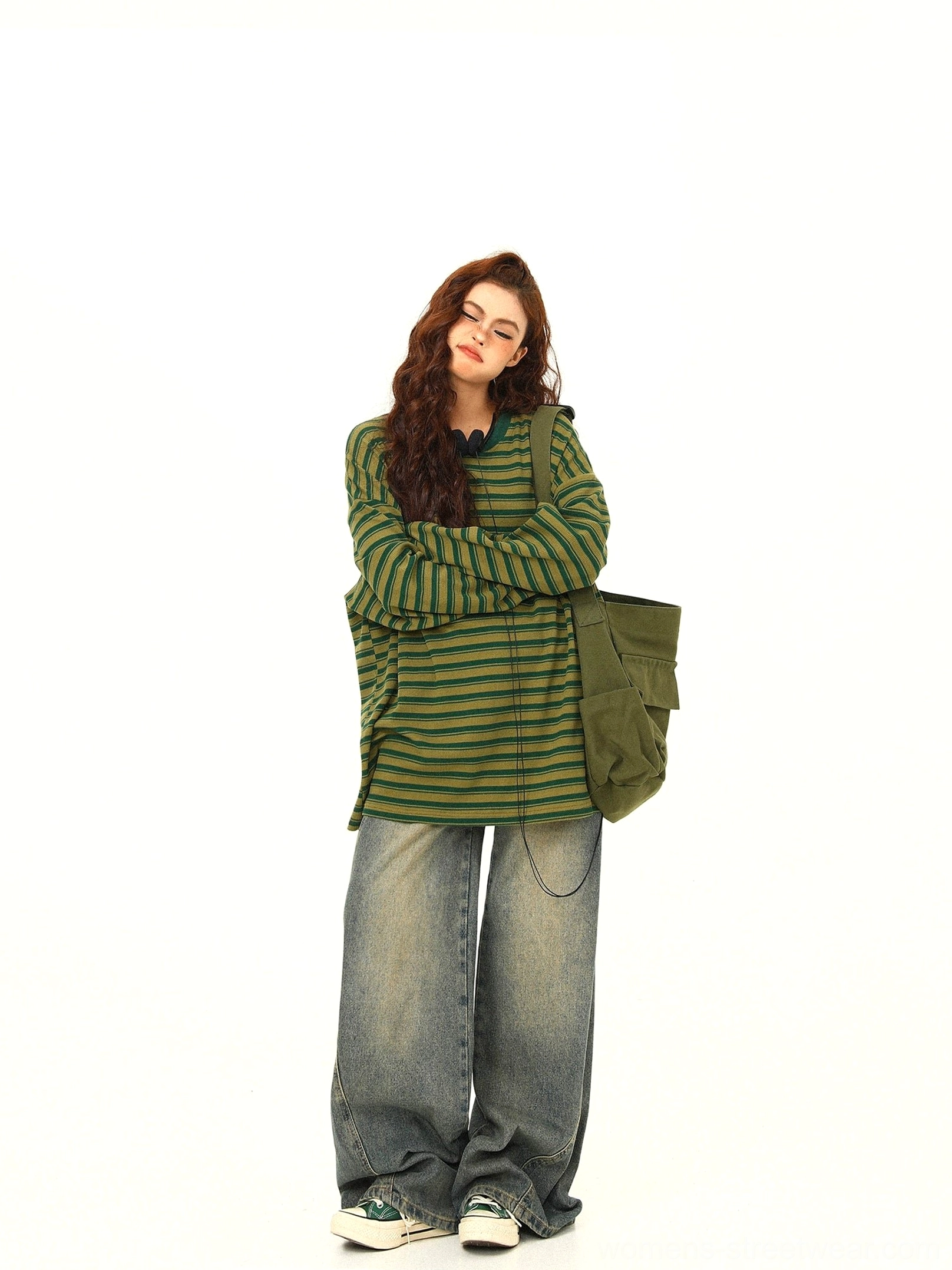 Full body front view of green and yellow striped oversized long sleeve tee with wide leg jeans and casual sneakers