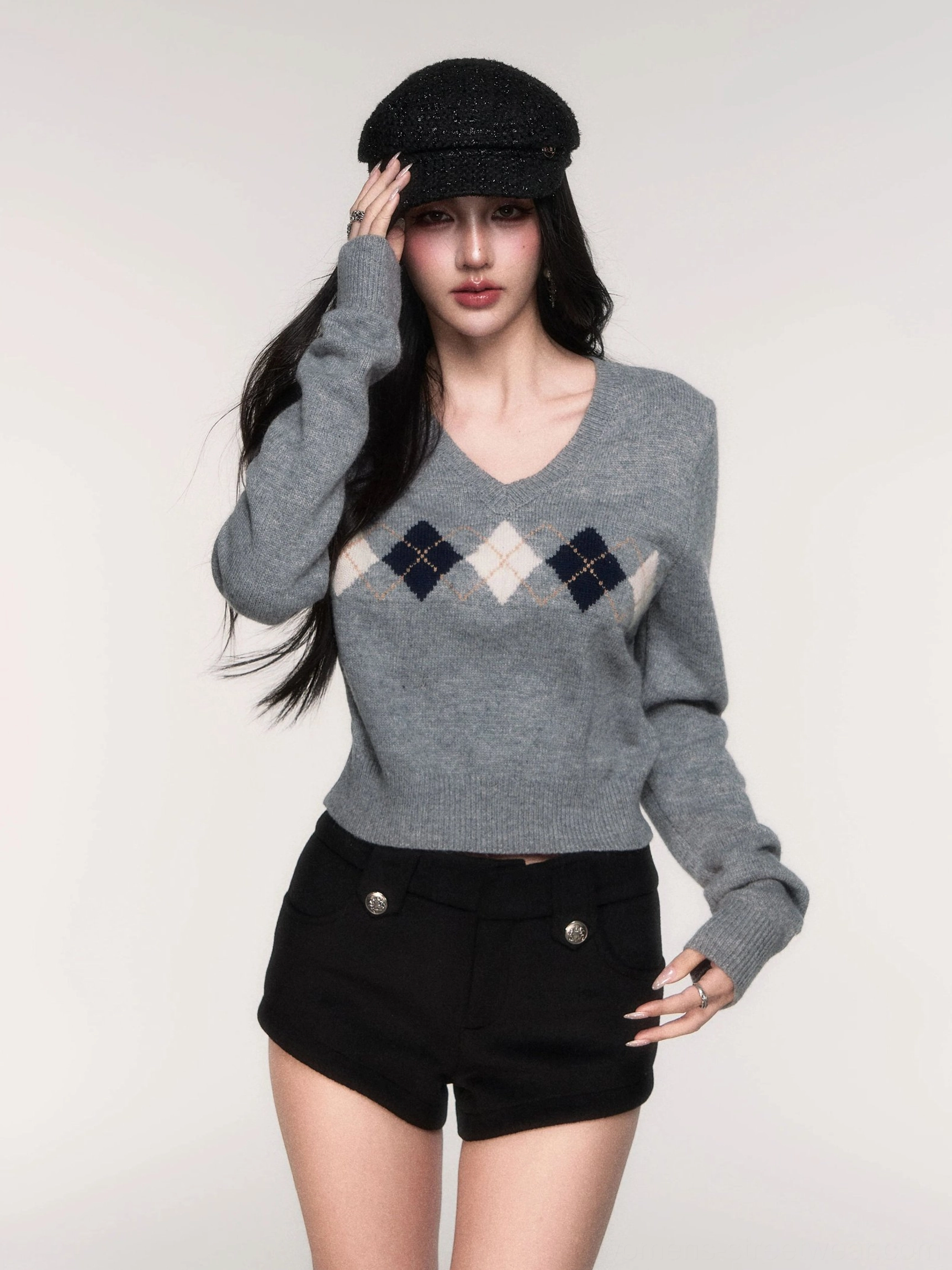 Close front view of women's grey argyle cropped V-neck knit sweater showing fitted waist length and diamond pattern