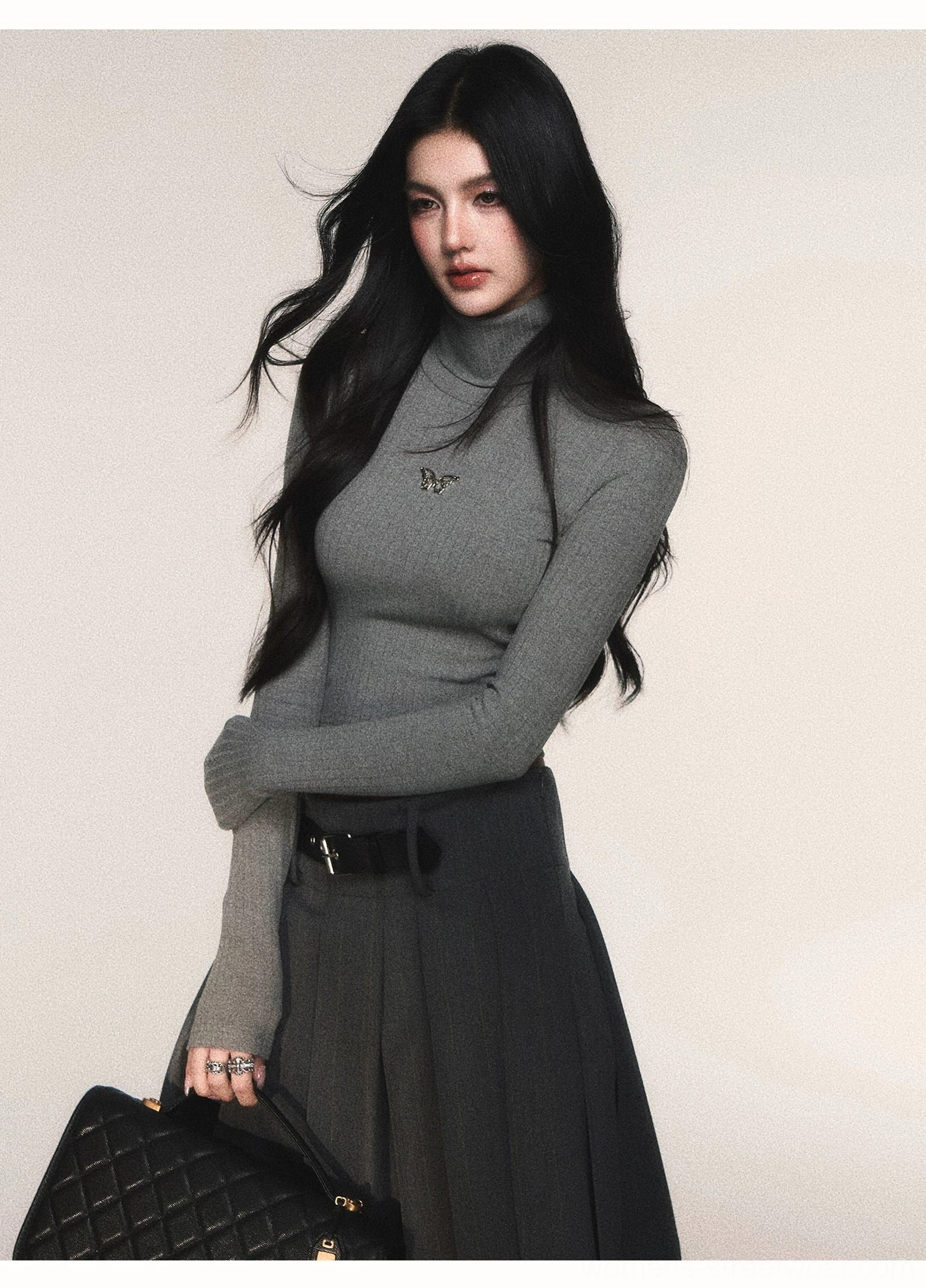 Grey butterfly cropped turtleneck knit top with ribbed texture styled with a dark pleated skirt and handbag