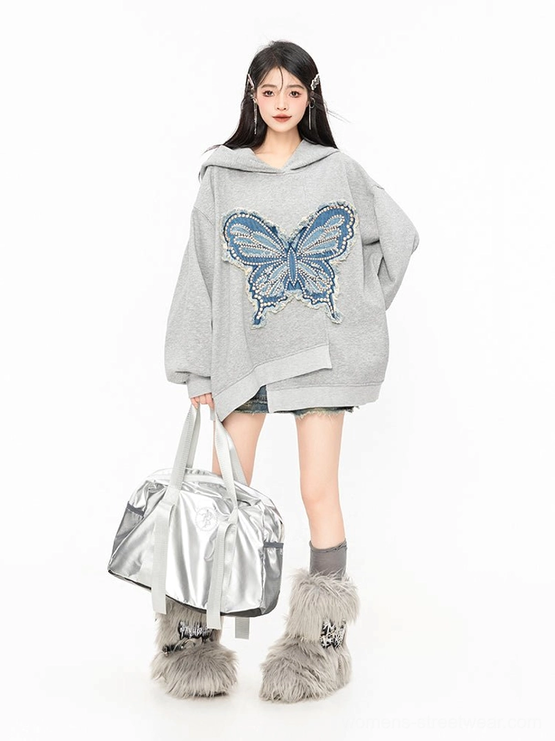 Side view of oversized grey butterfly hoodie styled with a silver duffle bag and fuzzy grey leg warmers for Korean streetwear