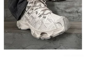 Grey chunky streetwear sneakers worn with dark denim showing woven mesh texture, geometric overlays, and thick textured platform outsole