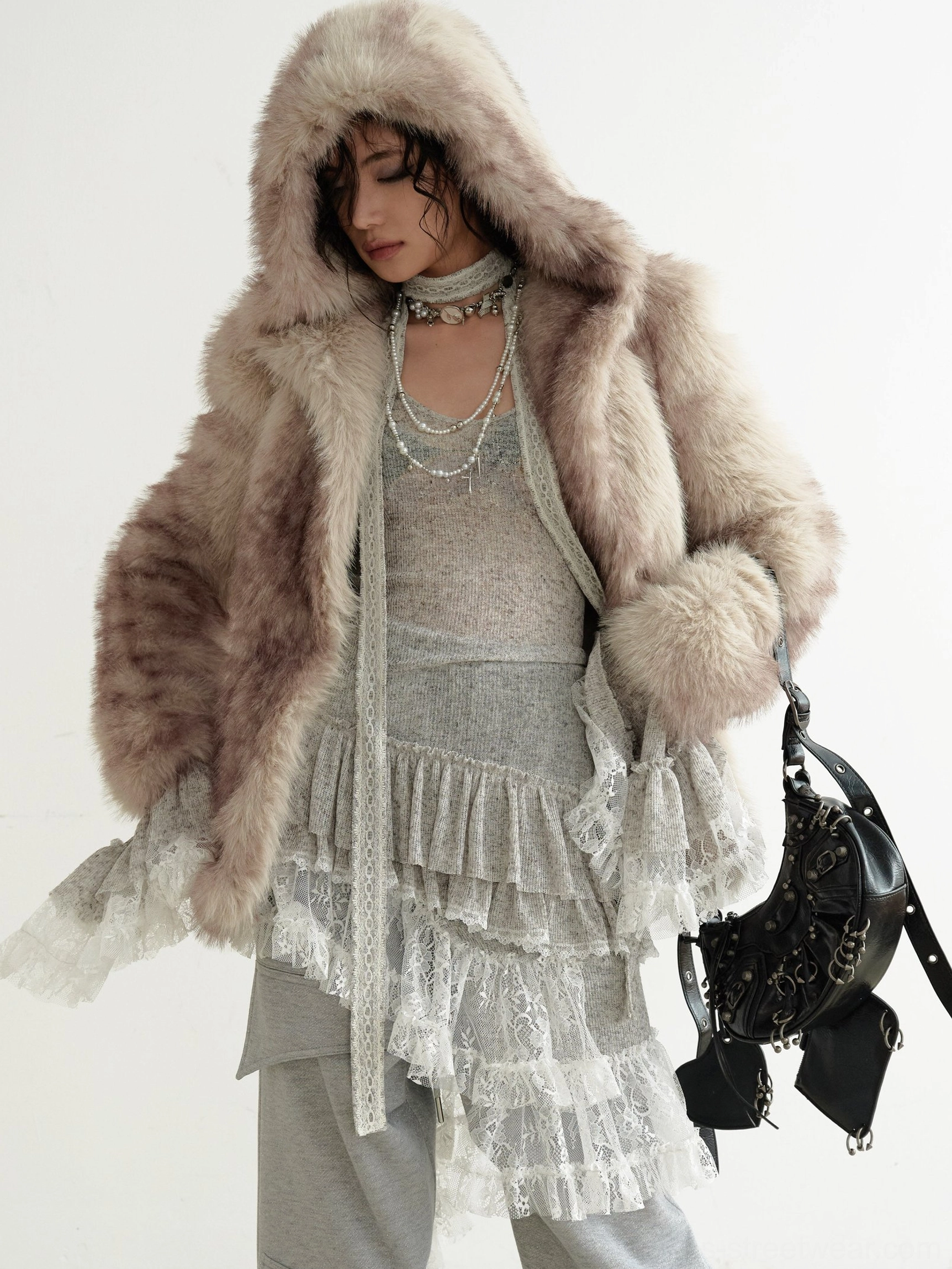 Grey asymmetrical lace knit dress styled beneath a fluffy brown hooded faux fur coat with layered necklaces for an elevated streetwear outfit
