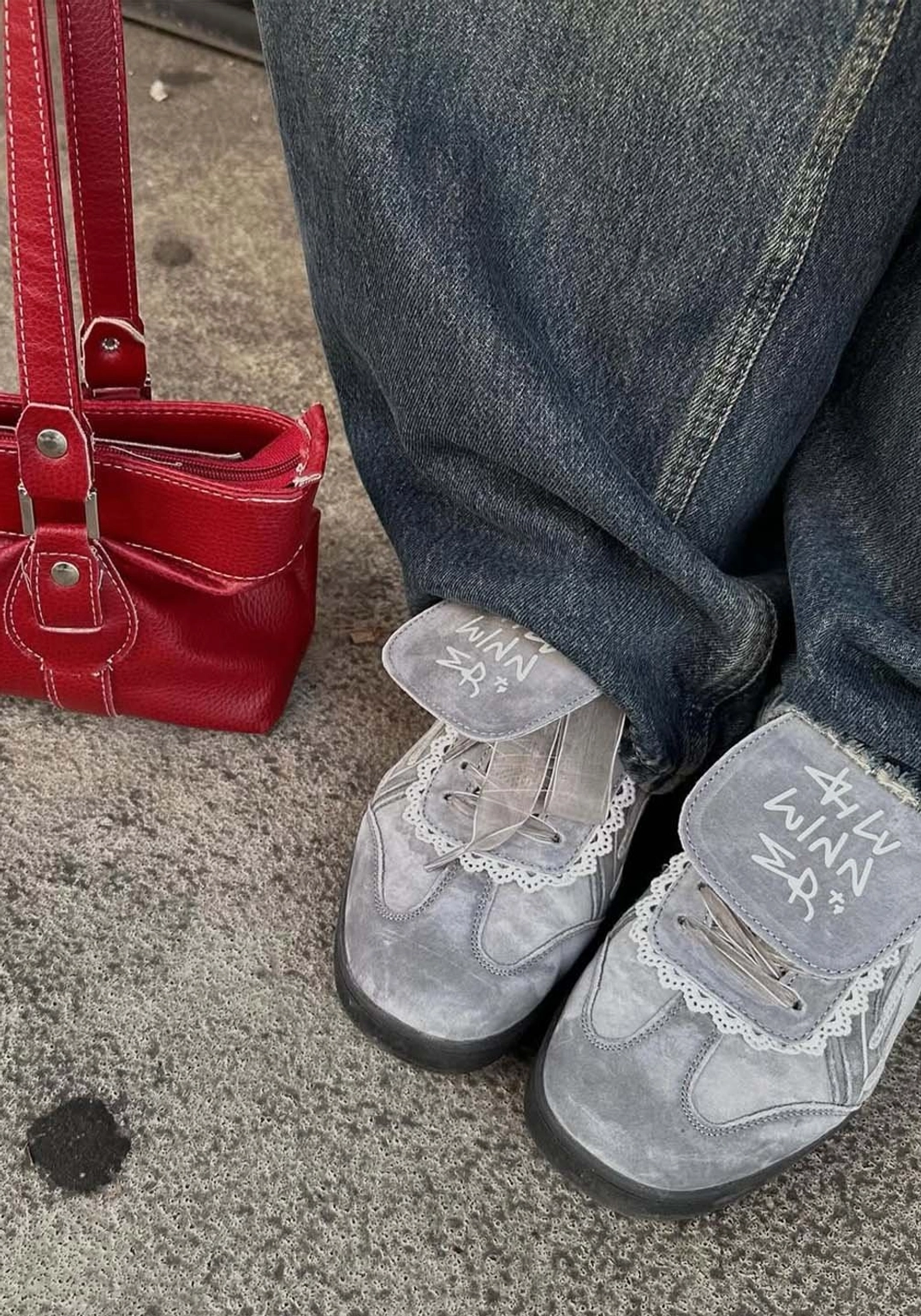 Grey graffiti flap retro trainer sneakers styled with blue denim jeans and red shoulder bag