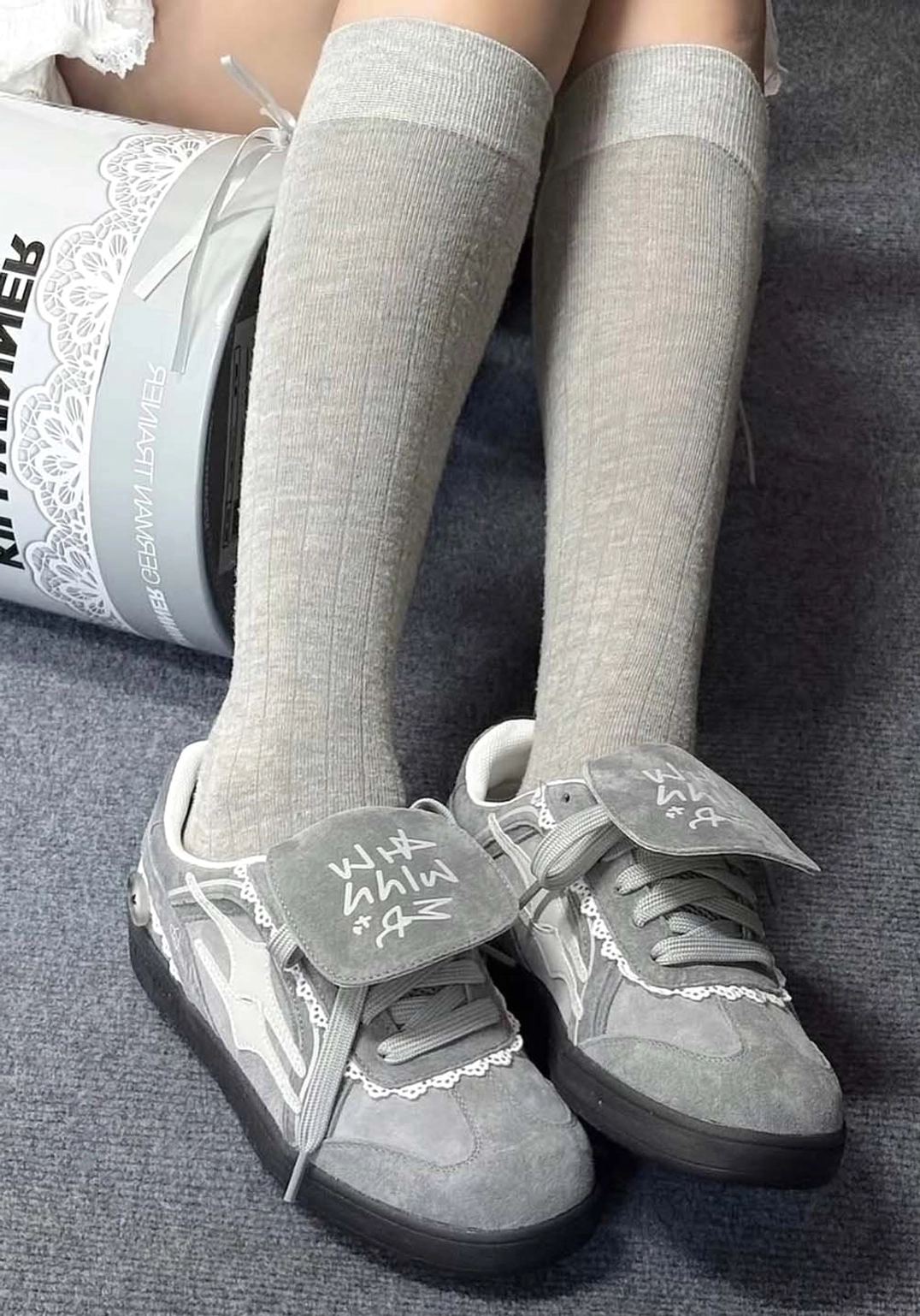 Top view of grey lace-wrapped retro trainer sneakers worn with grey knee-high socks