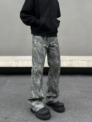 Front detail view of grey tie-dye marble wash flared jeans with relaxed leg shape, waist chain styling, and black platform boots