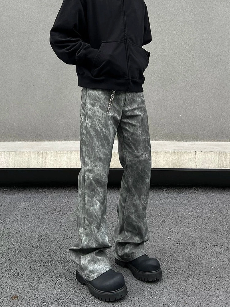 Front detail view of grey tie-dye marble wash flared jeans with relaxed leg shape, waist chain styling, and black platform boots