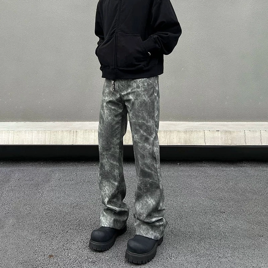 Low-angle front view of grey marble wash flared streetwear jeans with a loose stacked hem over black platform shoes