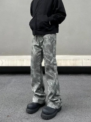 Front low-angle view of grey marble wash relaxed flared streetwear jeans styled with a black zip-up hoodie and black platform shoes