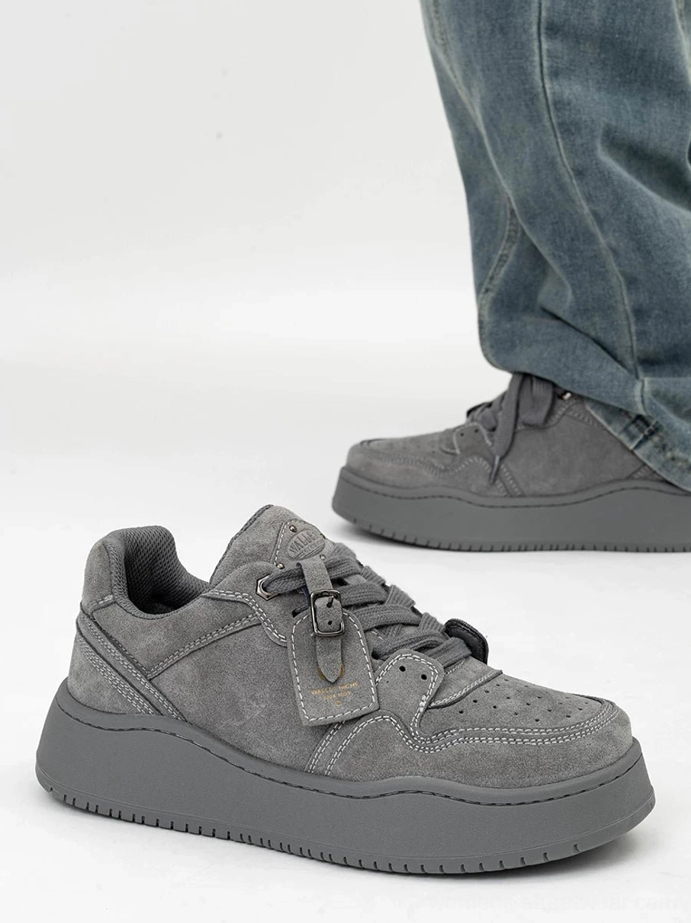Grey nubuck low-top platform skate sneakers with lace-up closure and chunky rubber sole worn with wide-leg blue jeans