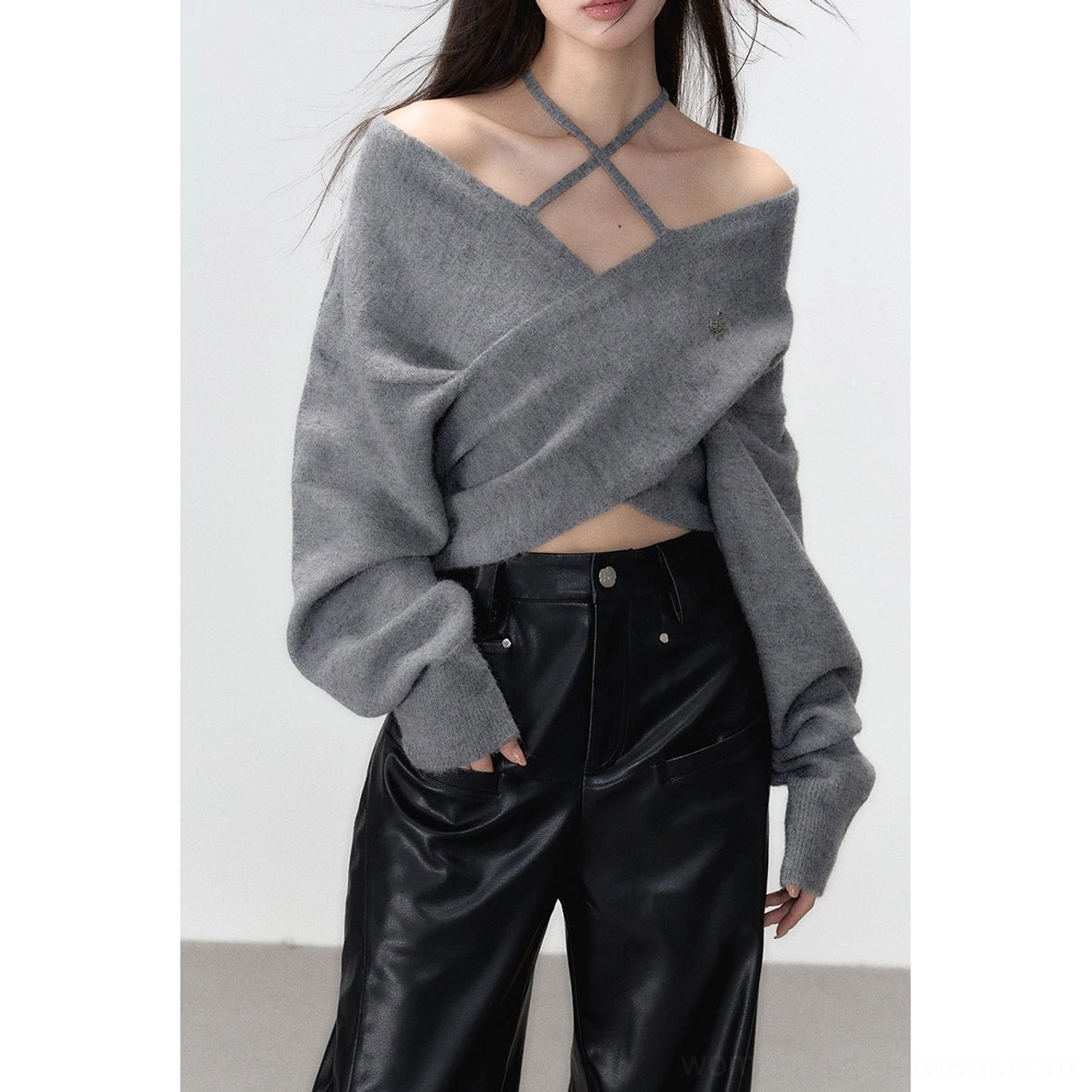 Model wearing a grey off-shoulder crisscross knit top with long sleeves styled with black leather pants for a modern Seoul streetwear outfit