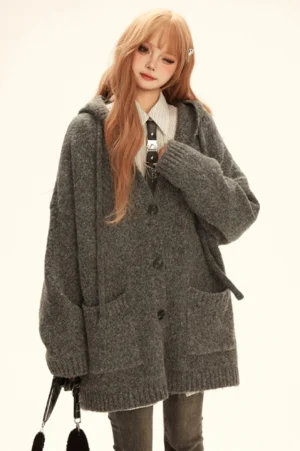 Grey oversized hooded boucle knit cardigan coat with button front and large patch pockets shown in front three-quarter view