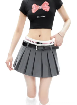 Close three-quarter view of grey pleated tennis mini skirt with striped waistband and styled black buckle belt