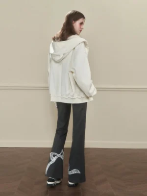 Back view of grey flared sweatpants with lace bow ribbon hem print, back pockets, and oversized cream hoodie styling
