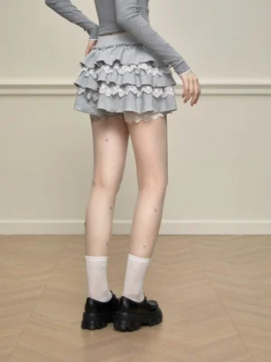 Back view of a grey tiered ruffle skort showing the cascading layered hem and white lace trim styled with ankle socks and platform shoes