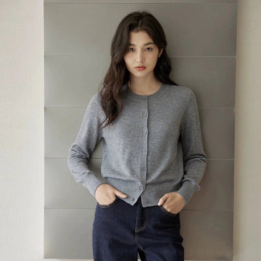 Grey women's soft fine-knit crew neck cardigan shown from the front with hands in jeans pockets and a clean basic silhouette