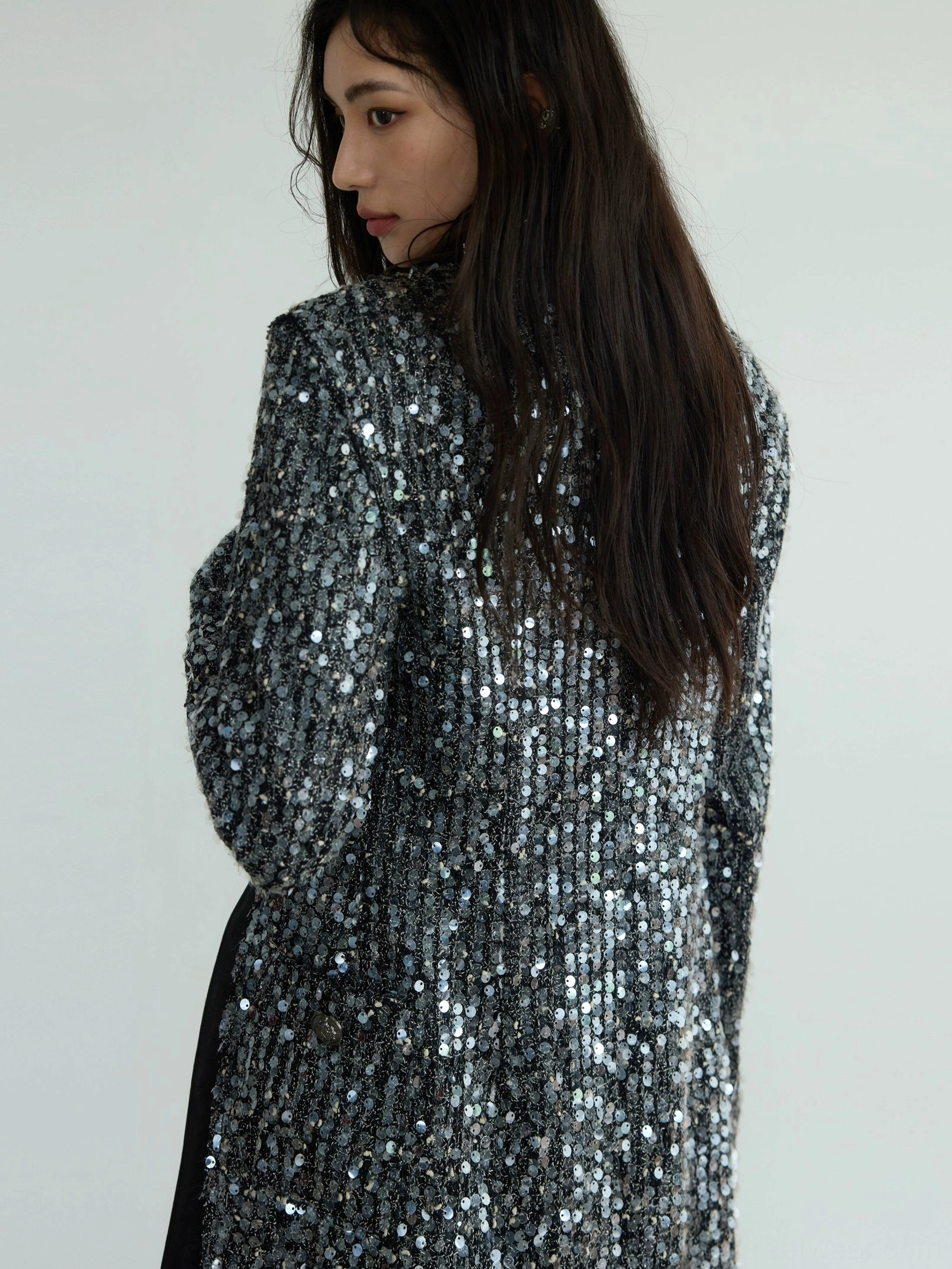 Close-up side detail of dense gunmetal silver sequin texture on an oversized blazer with contrasting black satin side trim