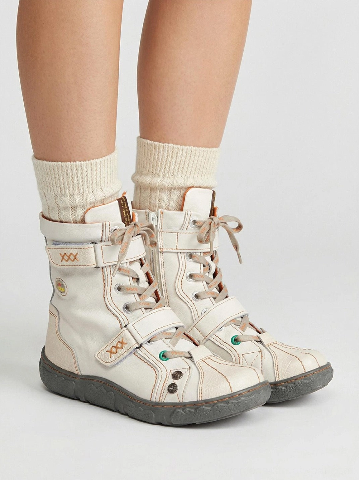 Model wearing white and green hand-stitched mid-calf streetwear boots with cream crew socks rear view