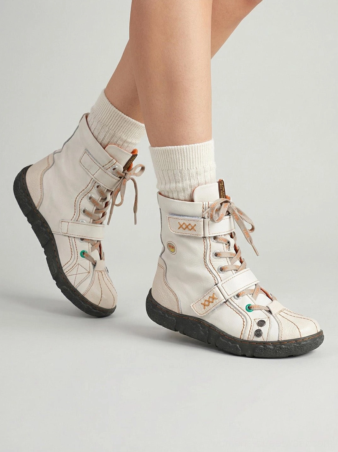 Model wearing white and green mid-calf streetwear boots showing lace-up upper and contrast toe details
