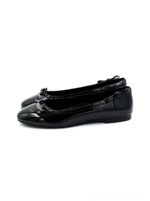 Black patent leather bow ballet flats in a side three-quarter view with glossy finish, rounded toe, ruffled heel trim, heart-back accent, and low flat sole