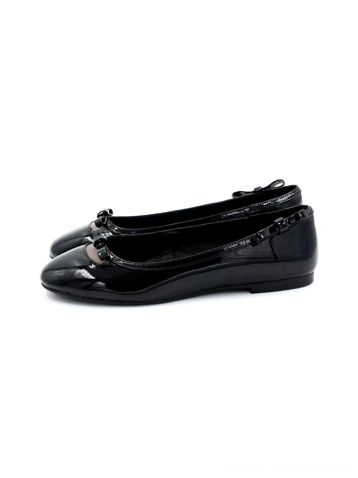 Black patent leather bow ballet flats in a side three-quarter view with glossy finish, rounded toe, ruffled heel trim, heart-back accent, and low flat sole