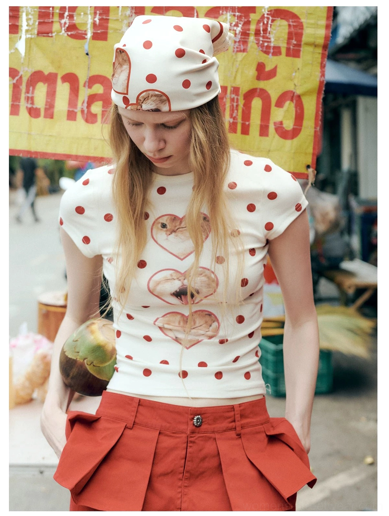 Three-quarter view of an off-white red polka dot cat graphic T-shirt paired with red pleated cargo shorts for a Korean-inspired streetwear look