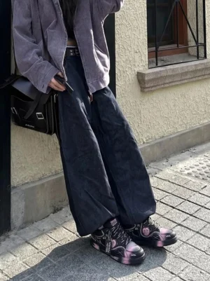 Heart graffiti low-top streetwear sneakers styled with a purple coat and wide-leg denim on an urban sidewalk