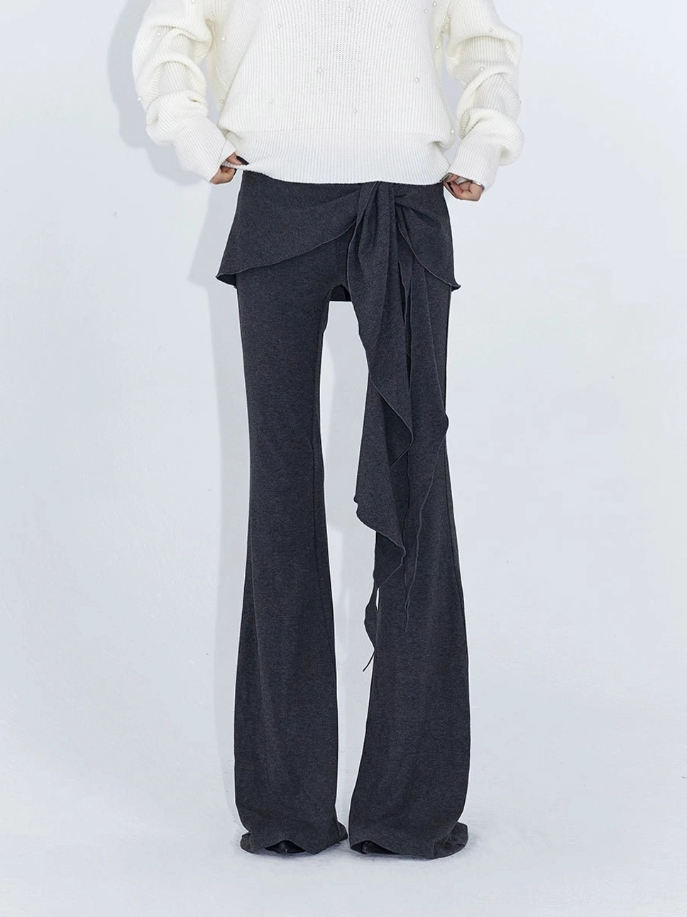 Heather gray asymmetric wrap drape flare streetwear pants styled with a white V neck knit sweater in a full body view