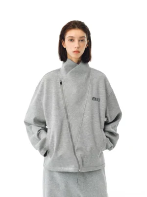 Heather gray asymmetric zip high-neck streetwear jacket on a female model with dropped shoulders, side pockets, and metal chest detail