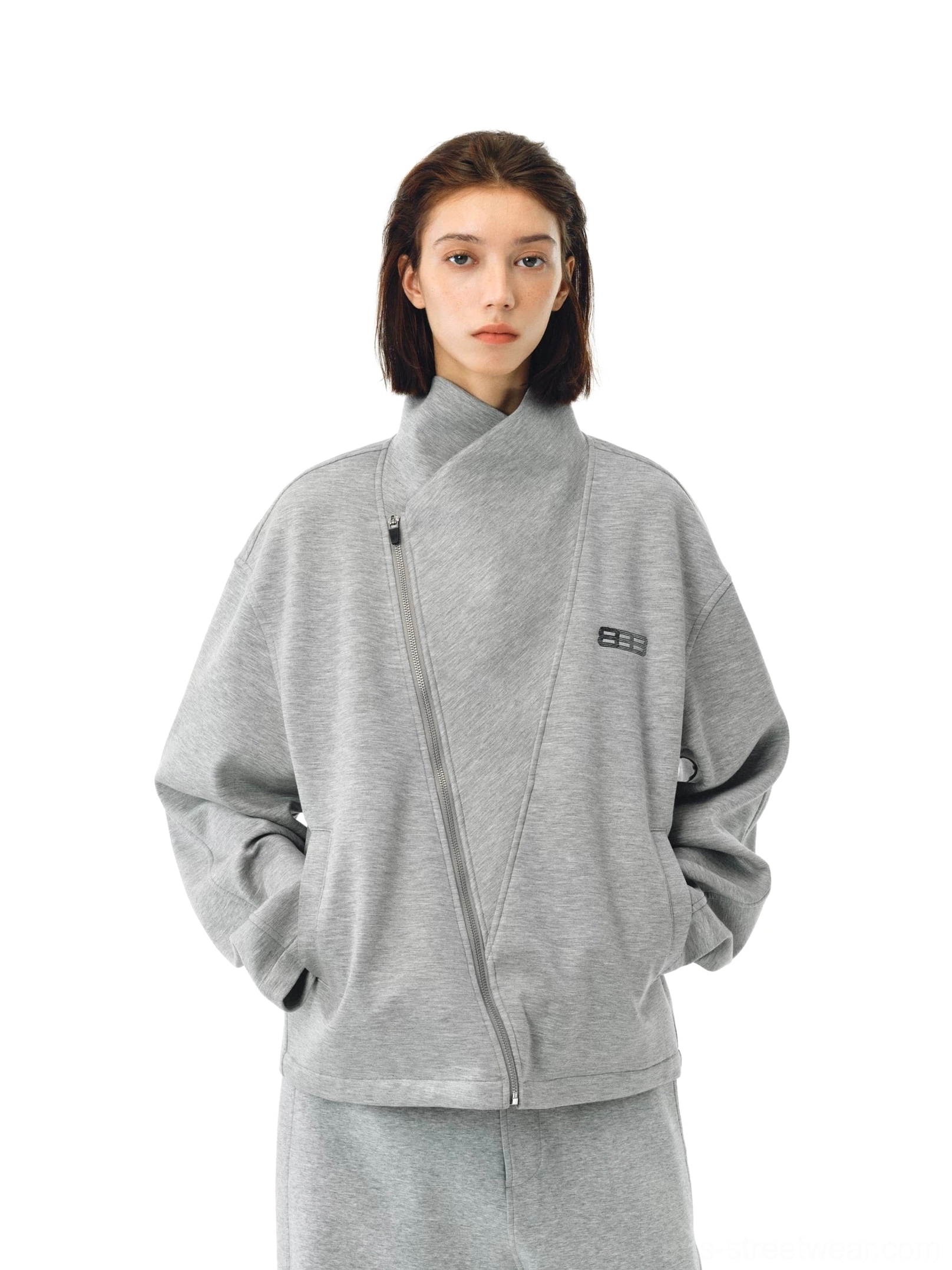 Heather gray asymmetric zip high-neck streetwear jacket on a female model with dropped shoulders, side pockets, and metal chest detail