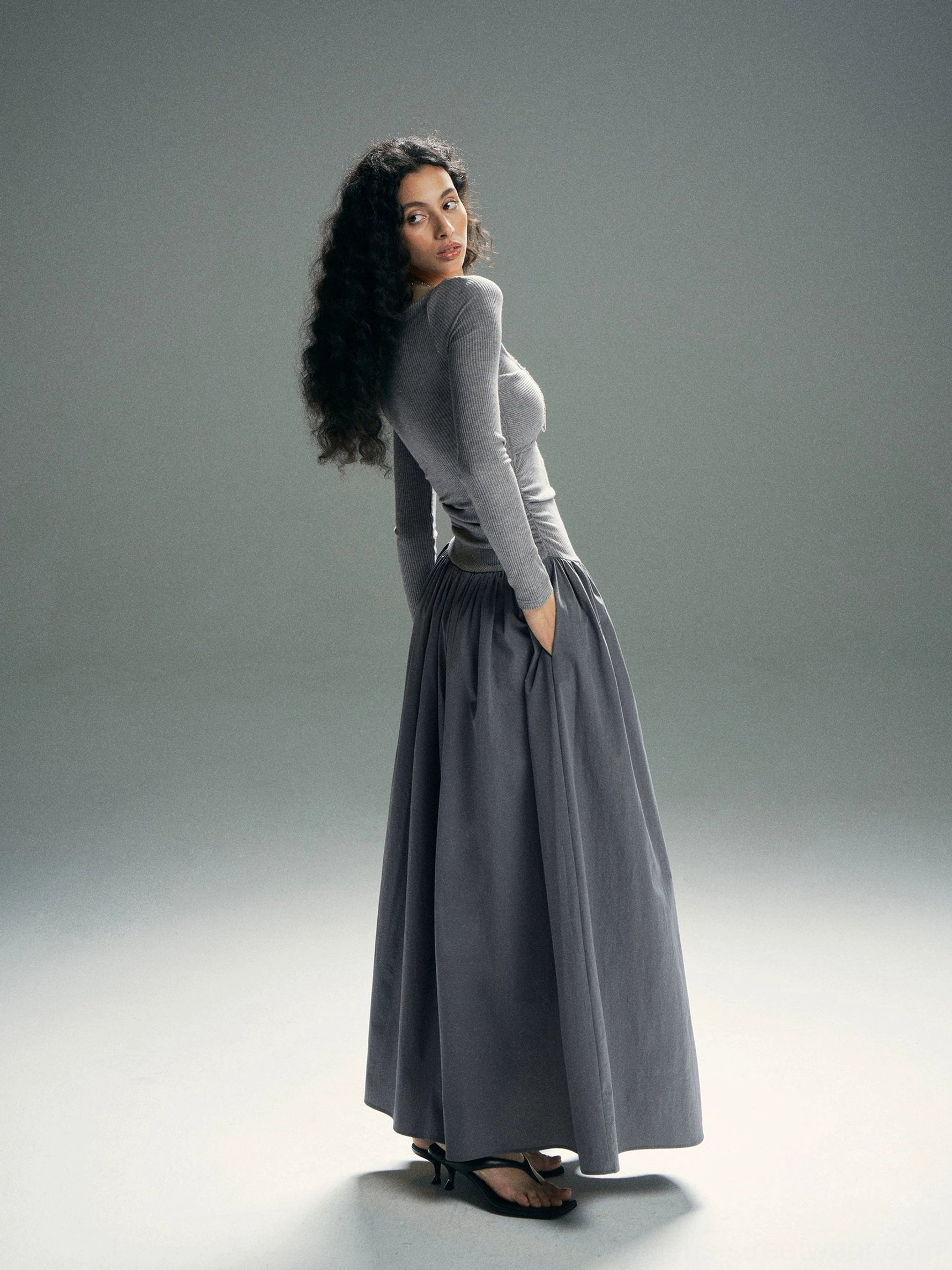 Heather gray asymmetrical cold-shoulder long-sleeve maxi dress shown from the rear with a ruched waist, flowing skirt, and side pockets