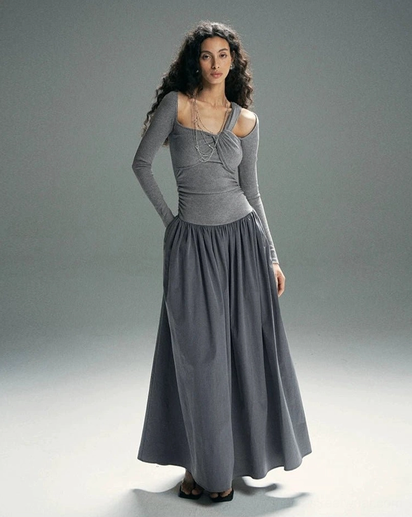 Heather gray asymmetrical maxi dress with chain-accented twisted neckline, long sleeves, hidden side pockets, and flowing A-line skirt