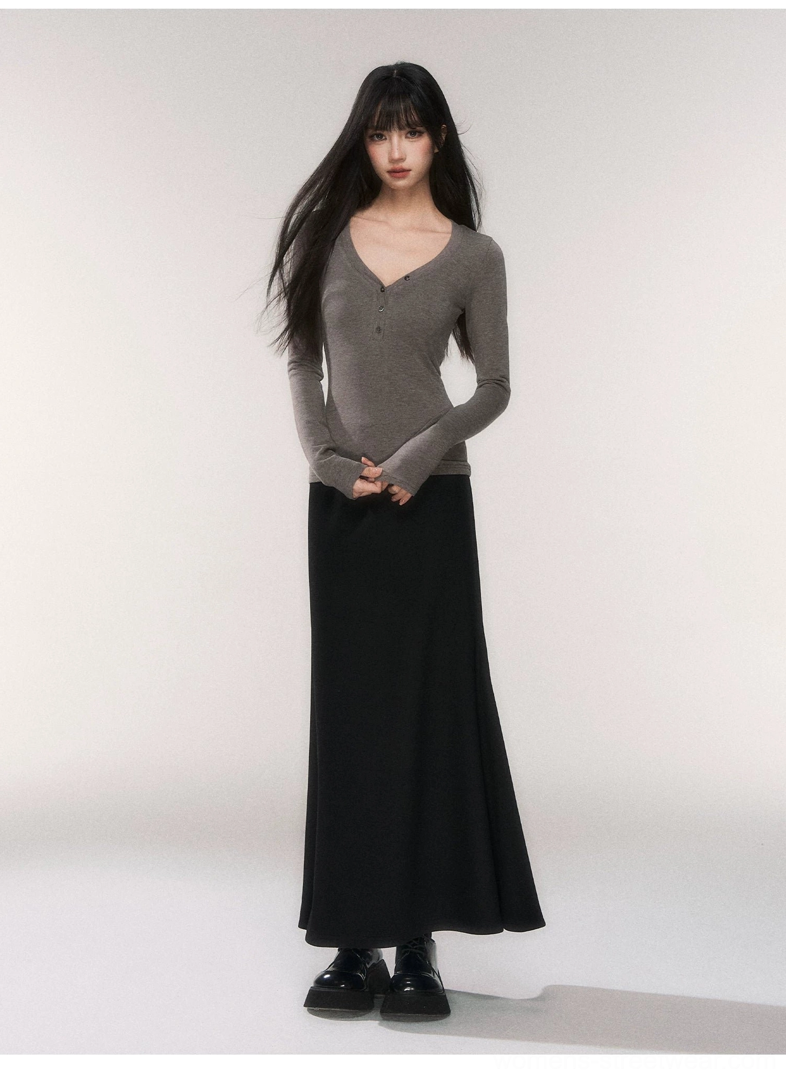 Full-body view of a heather gray slim fit henley knit top with long sleeves styled with a black floor-length maxi skirt