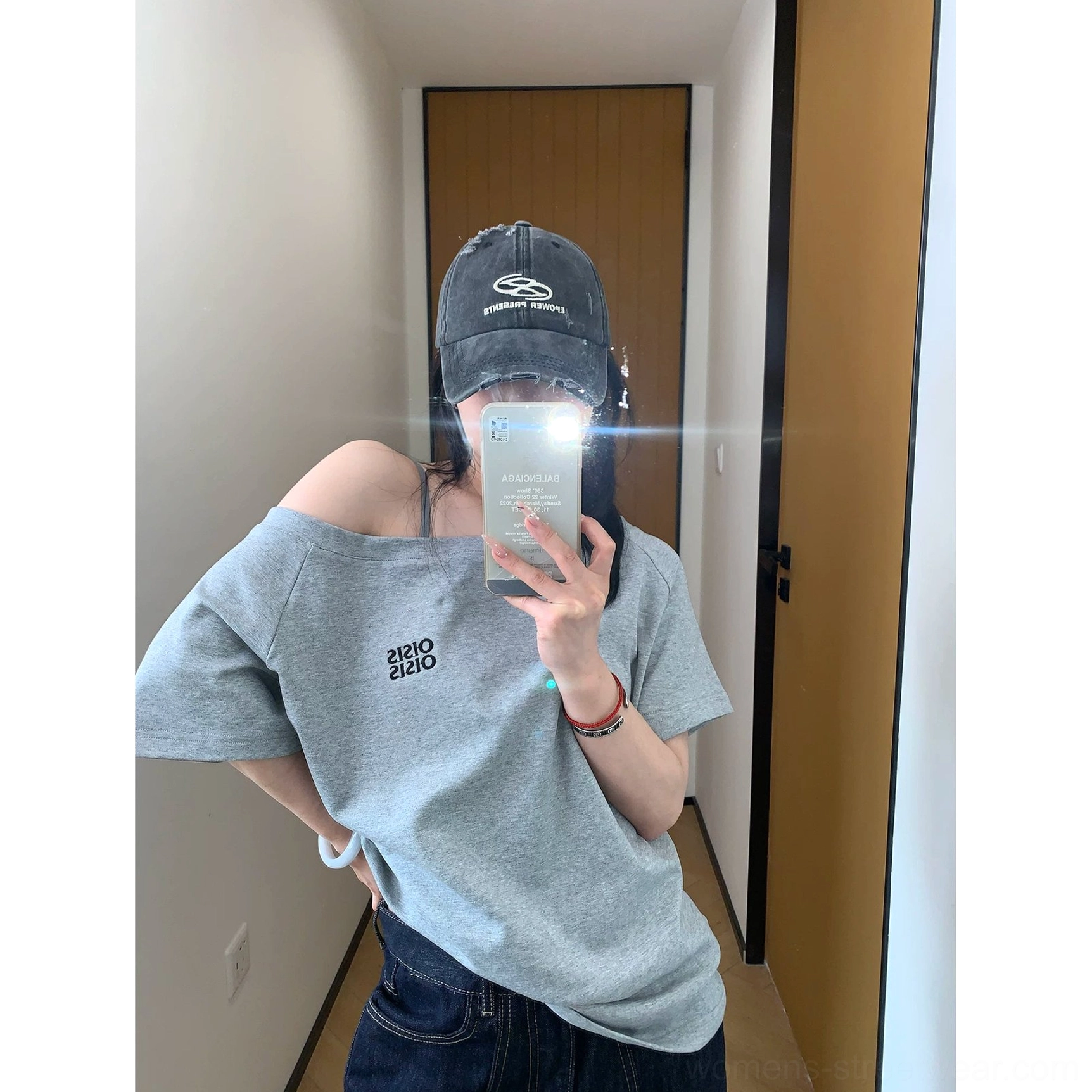 Side mirror view of a relaxed heather gray off-shoulder streetwear T-shirt paired with dark denim jeans