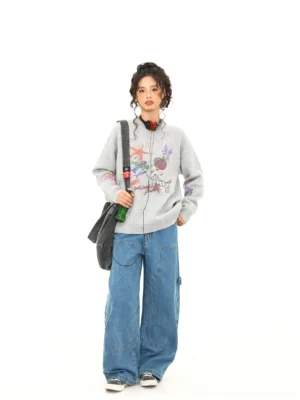 Full front view of heather gray oversized puppy doodle knit sweater with colorful cartoon graphics and black canvas bag