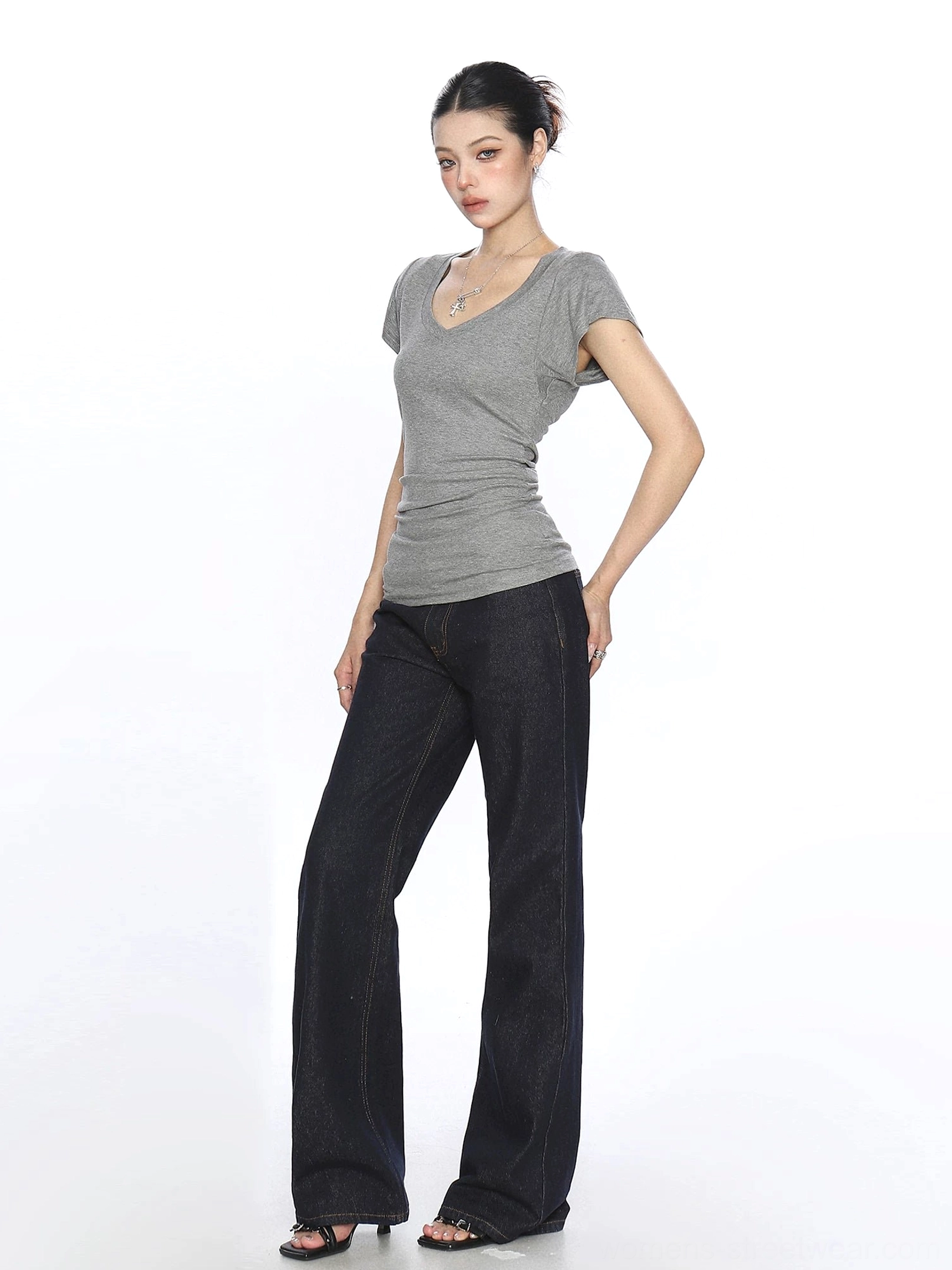 Side view of a heather gray slim ruched V-neck T-shirt with cap sleeves and dark wide-leg jeans