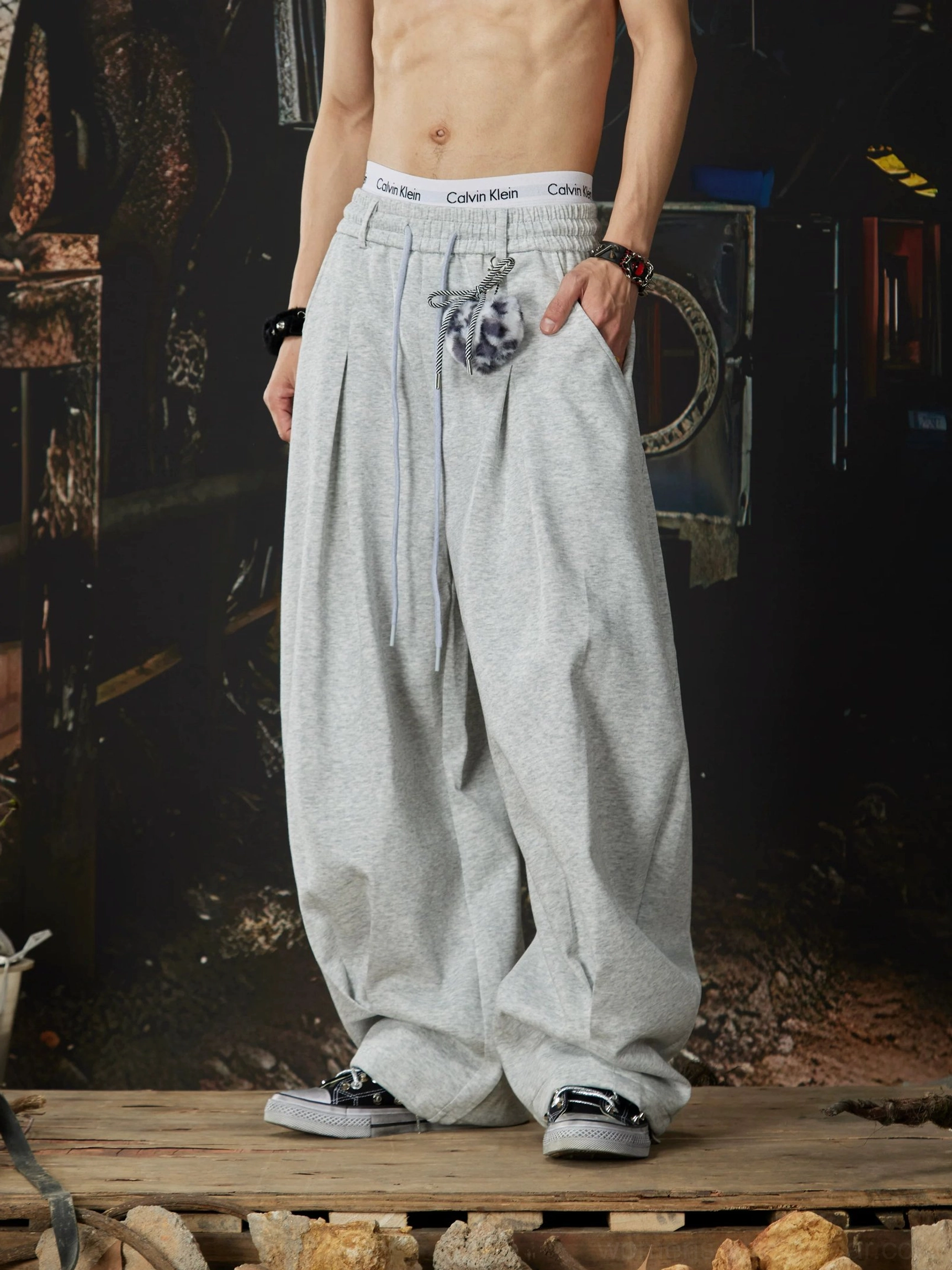 Heather grey wide-leg streetwear sweatpants with front pockets branded-style waistband decorative fuzzy charm and casual sneakers