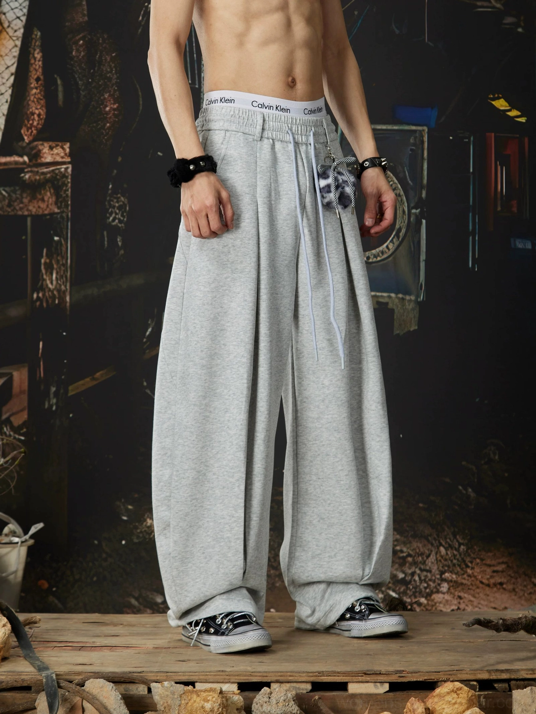 Side view of heather grey wide-leg sweatpants with loose streetwear fit adjustable drawstring waist and fuzzy leopard pendant
