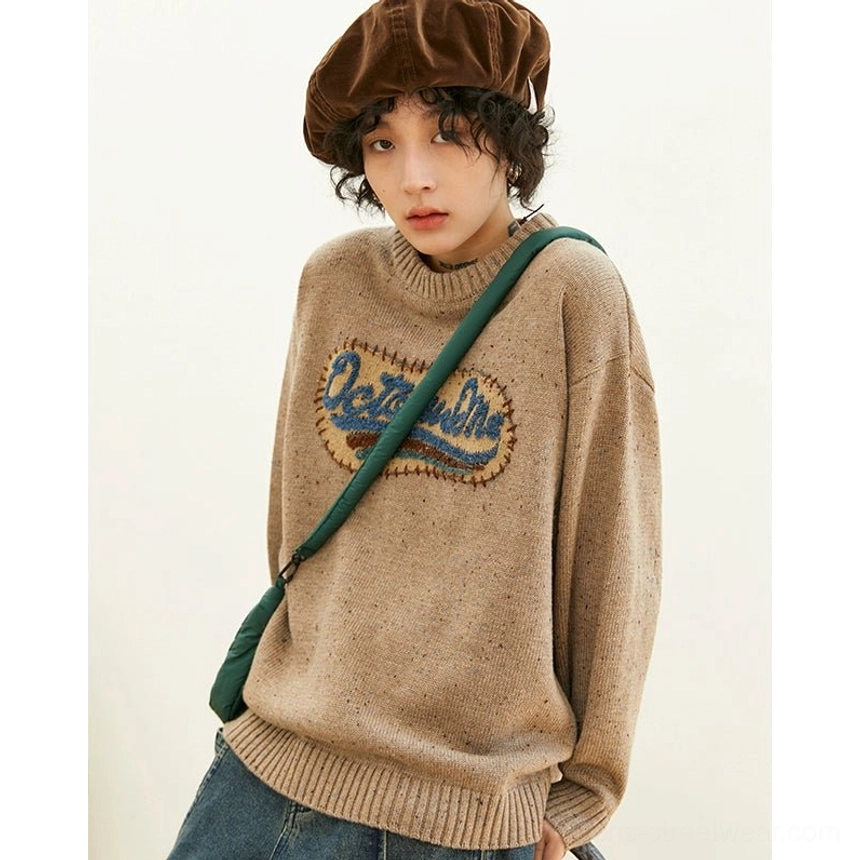 Heathered oatmeal beige gray oversized crewneck knit sweater with ribbed trims and dimensional embroidered chest patch styled with wide-leg jeans