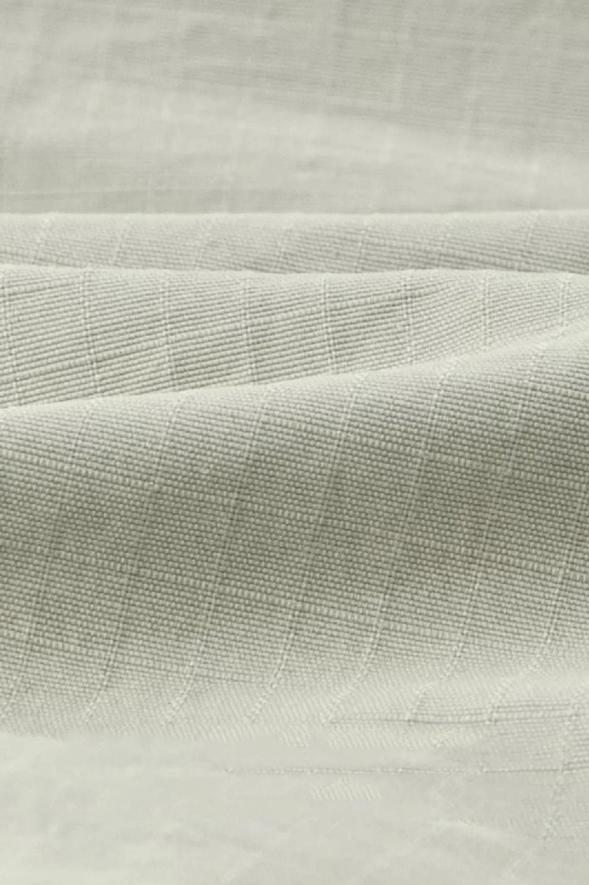Close-up view of breathable heavyweight cotton shorts fabric showing light khaki woven grid texture