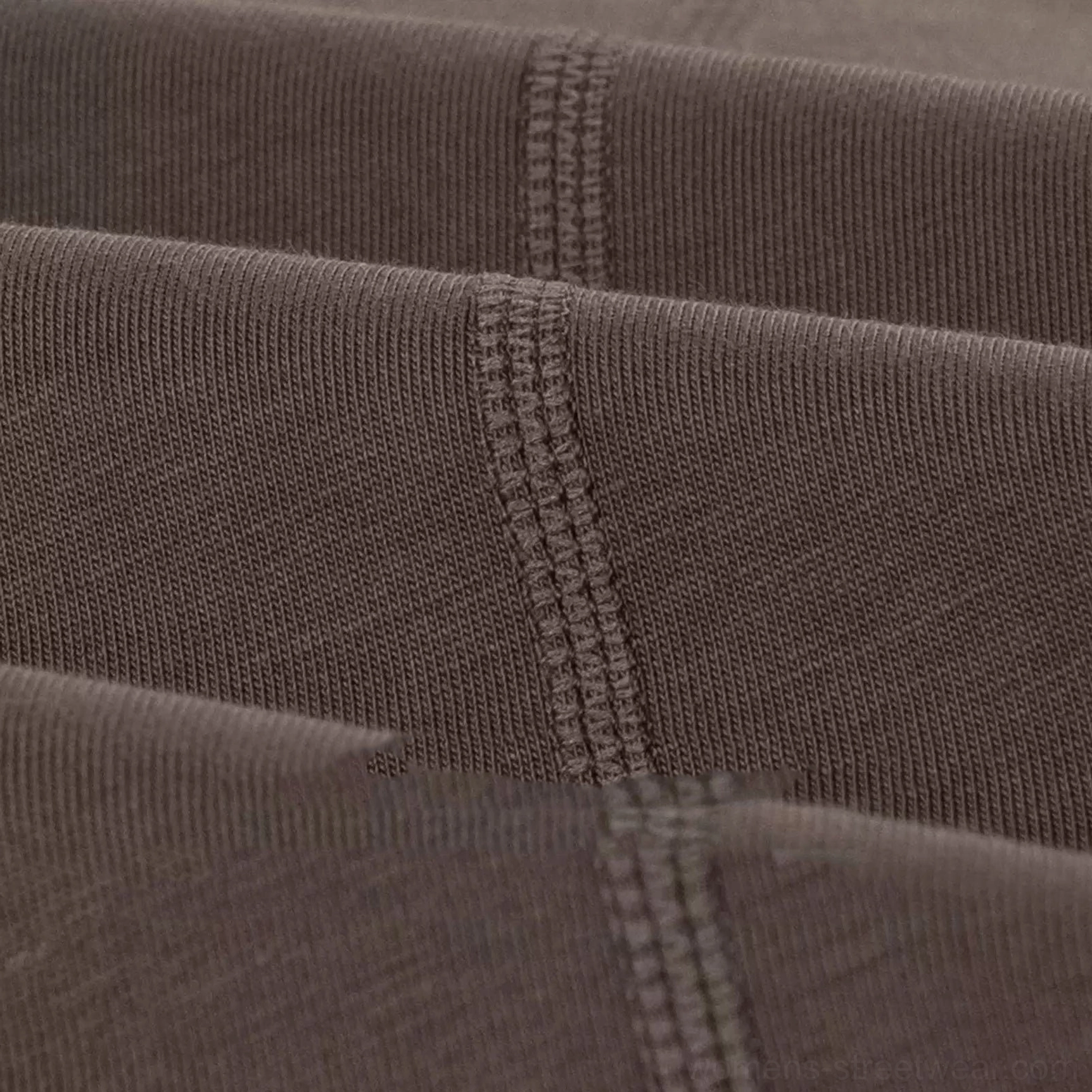 Macro seam detail showing sturdy topstitching and thick cotton construction on a dark taupe loose-fit streetwear T-shirt