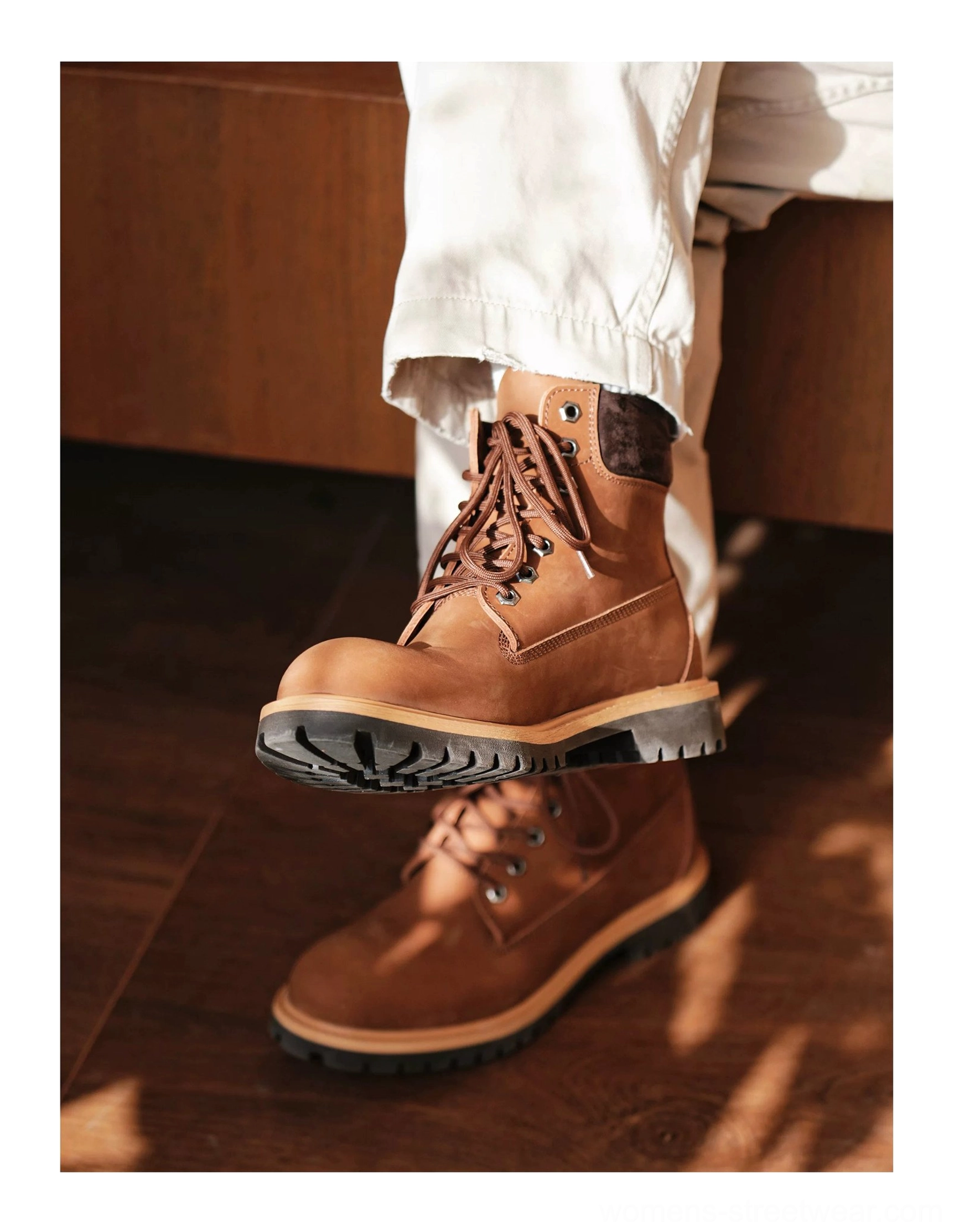 Two pairs of brown heritage leather work boots stacked on wooden floor showing padded collars and lug soles