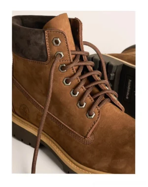 Dark brown heritage leather work boots close-up showing metal lace eyelets suede texture and padded ankle collar