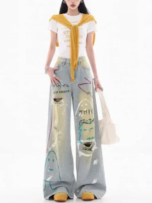 Front view of high-rise graffiti wide-leg jeans with faded blue acid-wash denim, relaxed loose fit, painted artwork, and distressed streetwear details